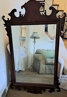 a large mirror sitting on top of a floor next to a couch in a living room