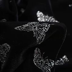 black and white photograph of shiny fabric with butterfly design on the side, closeup