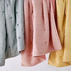 three different colored shirts hanging on a clothes line with one folded and the other unbuttoned