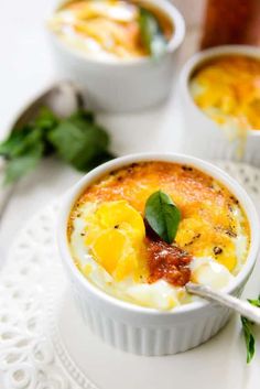 two bowls filled with soup on top of a white tablecloth next to spoons