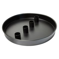 four black candles are placed in a metal tray