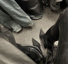 several pairs of black leather boots are sitting on the floor next to bags and luggage