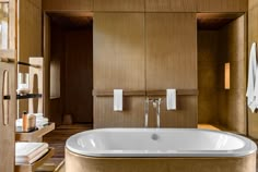 a large bath tub sitting inside of a bathroom next to a wooden cabinet and mirror