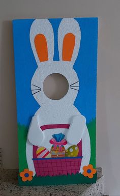 an easter bunny door hanger with eggs in a basket on a countertop next to a wall