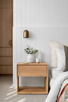 a bed room with a neatly made bed and two vases on the end table