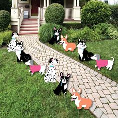 a group of dogs that are standing in the grass near a house and some bushes