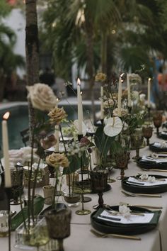 a long table is set with candles and flowers for an outdoor dinner party or celebration