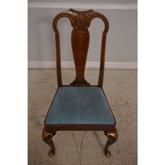 an antique wooden chair with blue upholstered seat