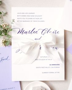 the wedding stationery is laid out on top of each other, including an envelope with a bow