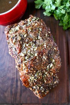 a piece of meat sitting on top of a wooden cutting board next to a cup of coffee