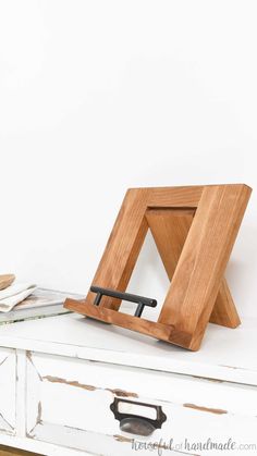 a wooden frame sitting on top of a white dresser next to a knife and fork