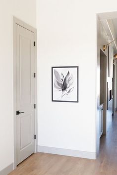 an empty hallway with a framed photograph on the wall and wooden floors in front of it