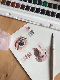 a close up of a piece of paper with watercolors on it next to a paintbrush