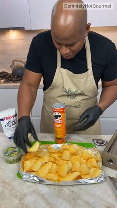 a man in an apron and gloves preparing food on a counter with a can of orange juice