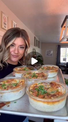 a woman standing in front of a table filled with pies on top of pans