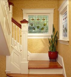 the stairs lead up to an entryway with a potted plant and stained glass window