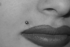 a woman's nose with a piercing on her left side, and the bottom part of her lip