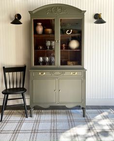 a green china cabinet sitting next to a black chair