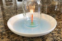 a lit candle in a glass jar on a plate