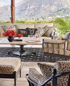 an outdoor patio with leopard print furniture and flowers on the table in front of it