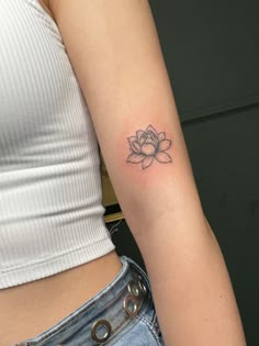 a woman's arm with a small flower tattoo on it