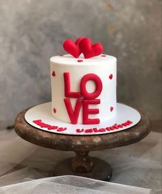 a white and red cake with the word love on it sitting on top of a table