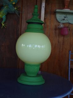 a green lamp sitting on top of a blue table next to a wall mounted bird