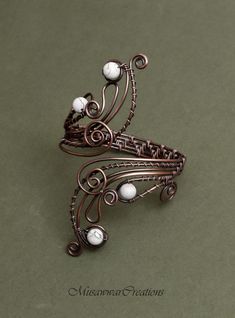 a brooch with pearls on it sitting on top of a green table next to another brooch