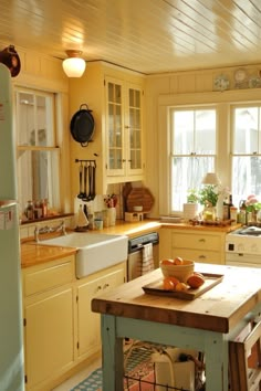 a kitchen with yellow walls and white cabinets, an island in front of the sink