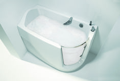 a white bath tub sitting inside of a bathroom next to a toilet paper dispenser