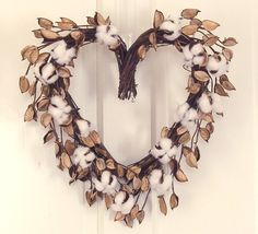 a heart shaped wreath with cotton and leaves