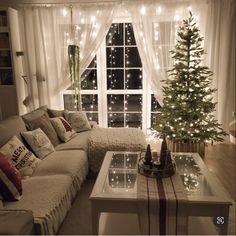 a living room filled with furniture and a christmas tree in front of a large window