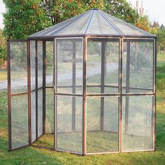 a small gazebo in the middle of a grassy area with trees and grass behind it