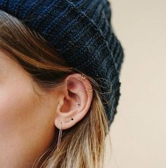 a close up of a person with ear piercings on their ears and wearing a beanie