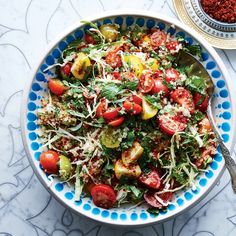 a blue and white bowl filled with lots of food on top of a marble table