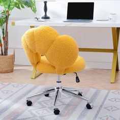 a yellow chair sitting in front of a desk with a laptop computer on top of it