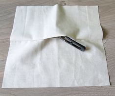 a pair of scissors laying on top of a piece of white paper next to a hole in the fabric