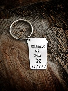 a metal keychain with the words you make me smile on it sitting on a piece of wood