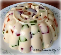 a cake that is sitting on a plate with white icing and multicolored designs