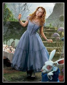 a woman in a blue dress standing next to a rabbit