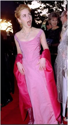 a woman in a pink dress with her mouth open and hands on her hips as she walks down the red carpet