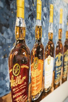 several bottles of alcohol are lined up on a shelf in front of a blue background