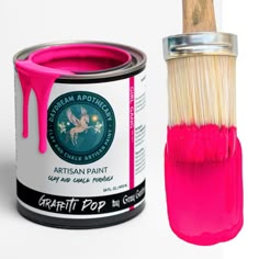 a pink paint can with a brush in it next to a tin of bright pink acrylic