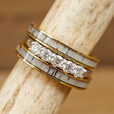 three gold and silver rings with white stones on each ring, sitting on a wooden stand