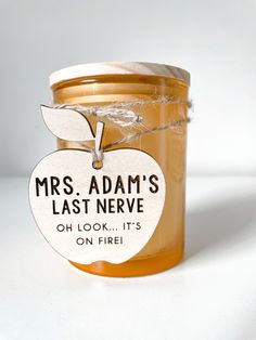 a jar of honey with an apple shaped label hanging from it's lid that says, mrs adam's last neve oh look - it's on fire