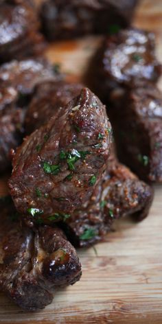 some meat is sitting on a wooden cutting board with parsley sprinkled on it