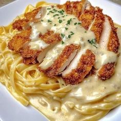 a white plate topped with pasta covered in sauce and chicken breast pieces on top of it