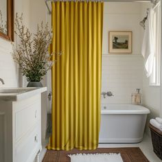 a yellow shower curtain in a white bathroom with a rug on the floor next to it