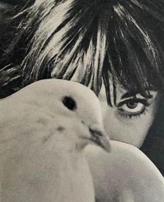 a woman holding a white bird in her right hand and looking at it's face