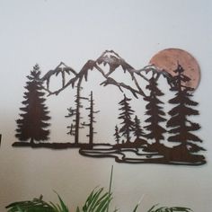 a metal wall art depicting mountains and trees